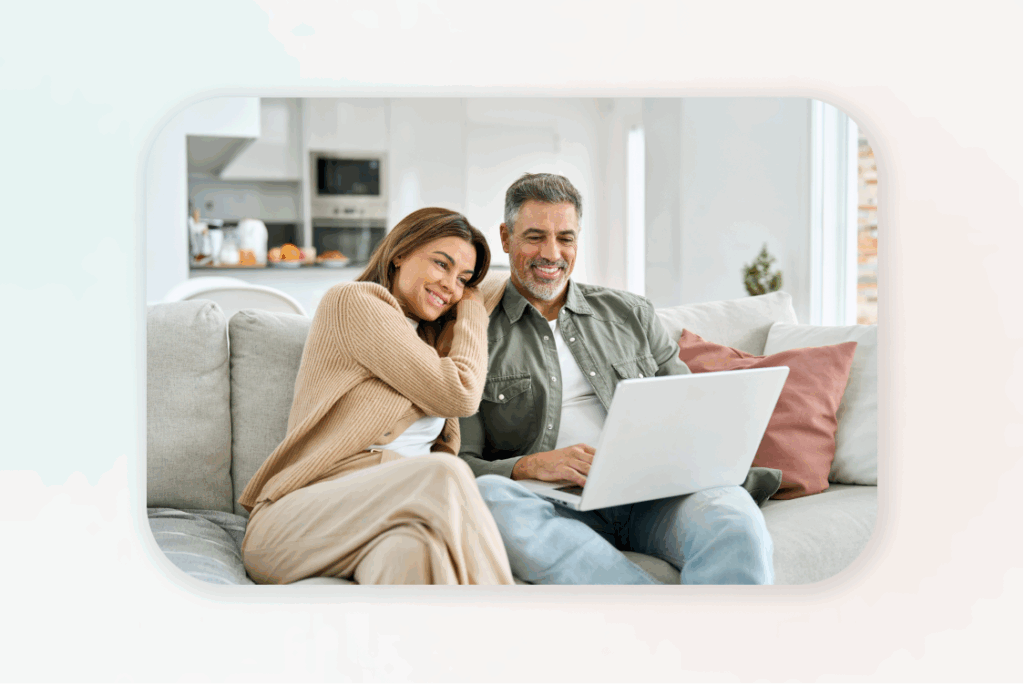 Couple sitting on couch using laptop together – earning money from home online.