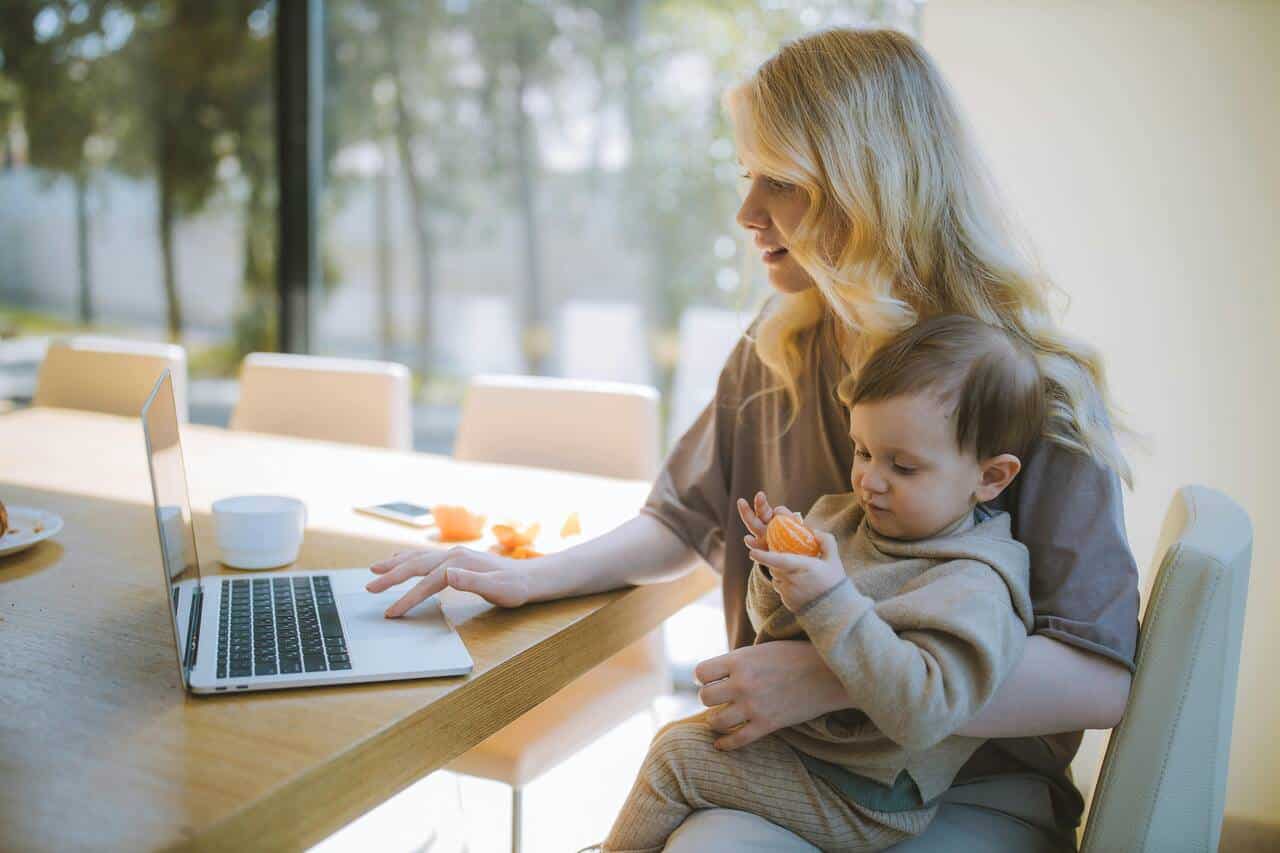 Woman working on laptop with child - balancing motherhood and entrepreneurship