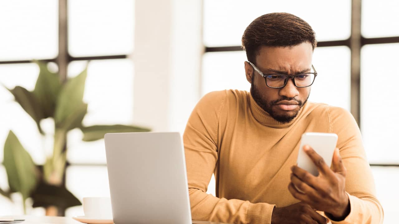 Guy confused with phone and laptop showing common business mistakes