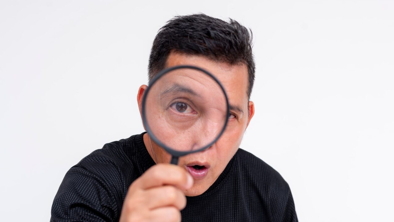 Guy holding magnifying glass looking for opportunities