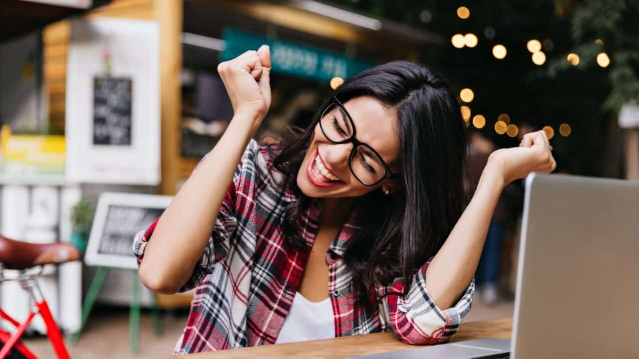 12_happy_freelancer_celebrating_success_at_cafe_with_laptop