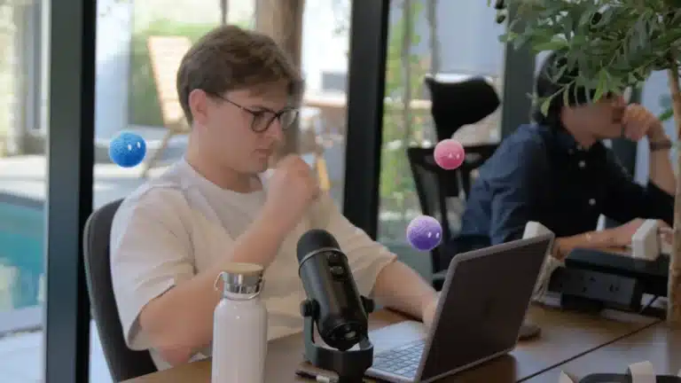 Professional reviewing work on a laptop with colorful Nas AI agents nearby.