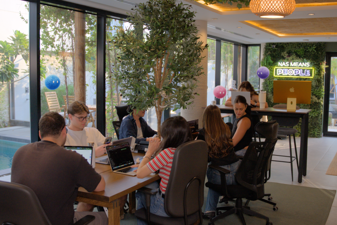Team collaborating around a table at Nas House with Nas AI agents.